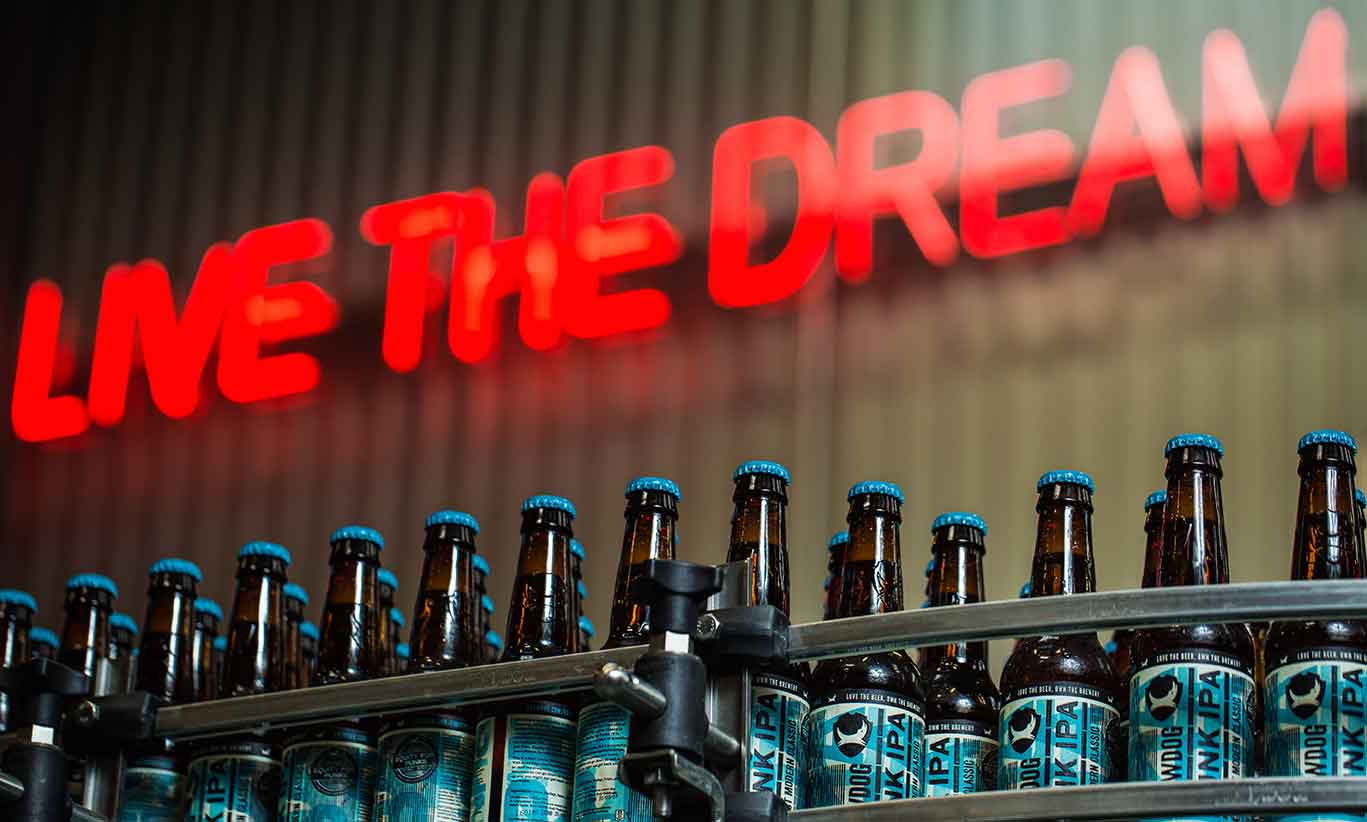 Punk-IPA Botellas de punk IPA en cinta embotelladora con mensaje motivador de fondo